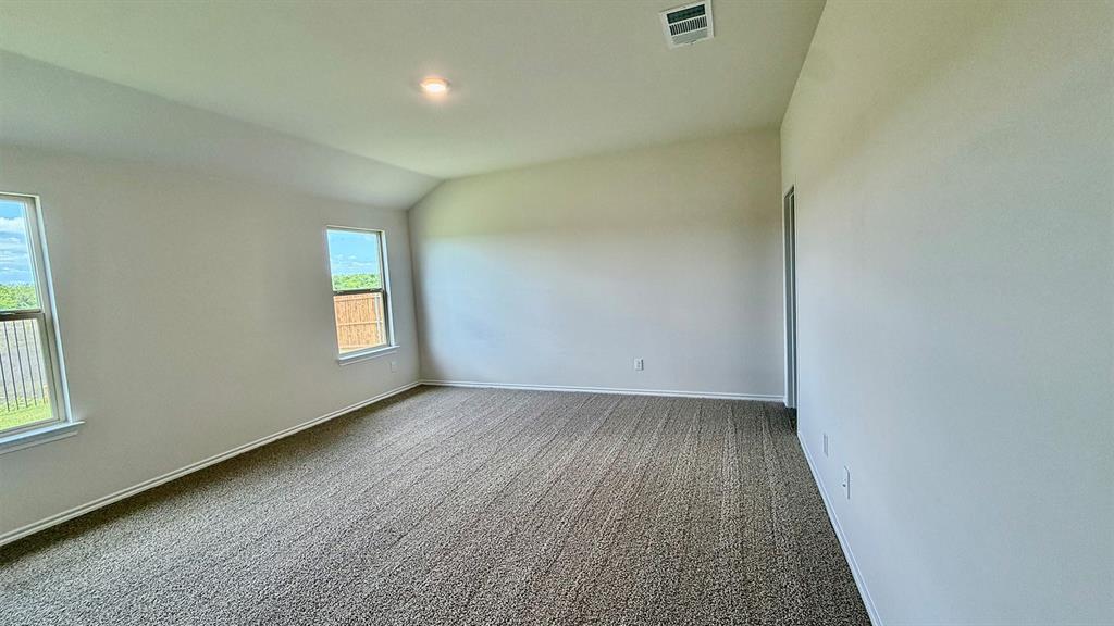 2003 Reveille Way Terrell, TX 75160 - Photo 10 of 25 Spacious room featuring vaulted ceilings, neutral-toned carpeting, two windows with white trim, and light-colored walls