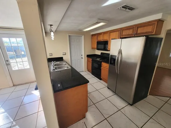 a kitchen with stainless steel appliances granite countertop a refrigerator a sink and a stove