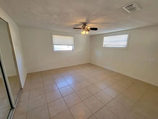 an empty room with windows and fan