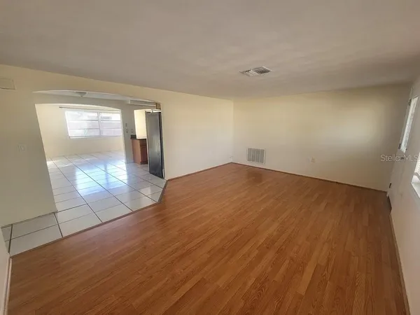 an empty room with wooden floor and mirror
