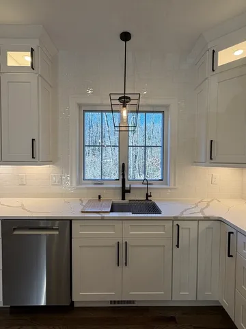 a kitchen with granite countertop a sink and white cabinets