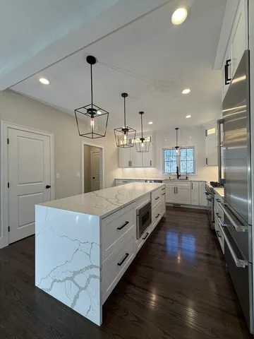 a large kitchen with stainless steel appliances granite countertop a stove a sink dishwasher a refrigerator and a oven with wooden floor