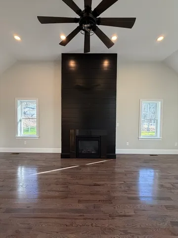 a view of an empty room with wooden floor and a fireplace