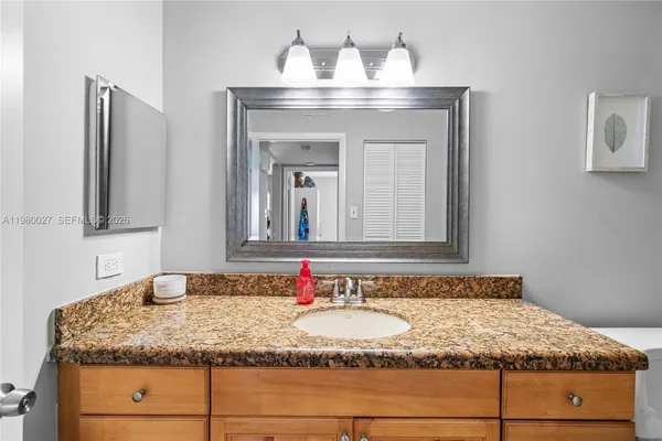 a bathroom with a granite countertop sink and a mirror
