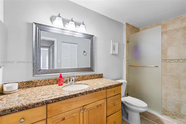 a bathroom with a granite countertop sink toilet and shower