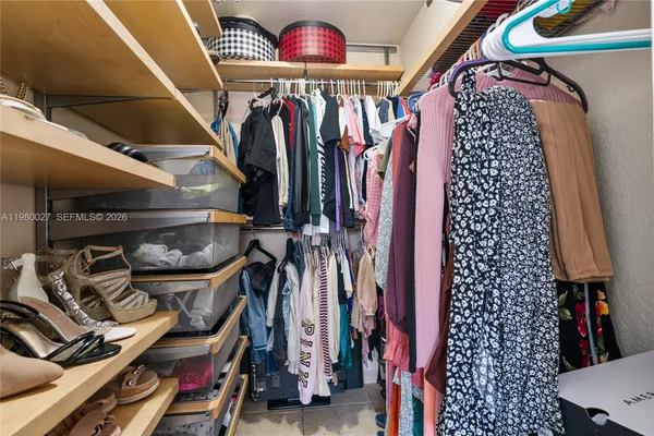 a view of walk in closet with clothes and shoes
