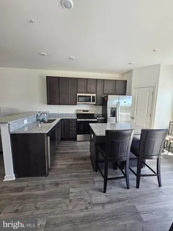 a kitchen with a stove a sink dishwasher a dining table and chairs with wooden floor