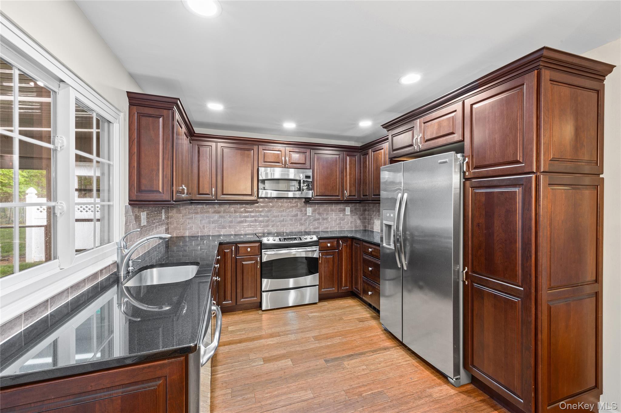 220 Belfast Lane Ridge, NY 11961 - Photo 21 of 44 a kitchen with granite countertop stainless steel appliances a refrigerator a sink a stove a microwave cabinets and a dining table