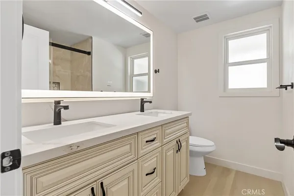 a bathroom with a granite countertop sink a toilet and a window