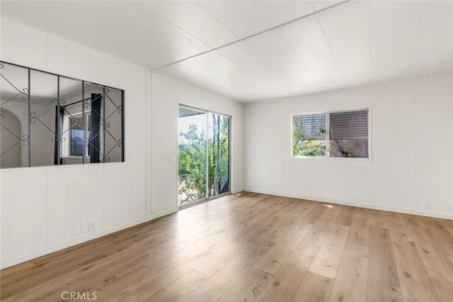 a view of an empty room with a window and wooden floor