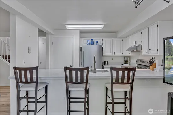 a kitchen with stainless steel appliances a dining table chairs and a refrigerator