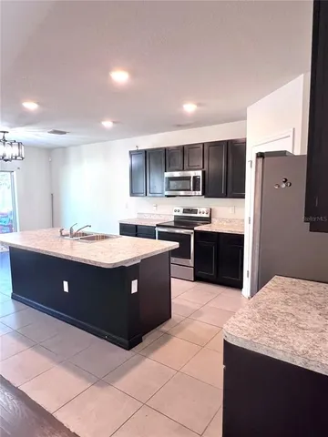 a large kitchen with kitchen island a sink a stove a refrigerator and a oven