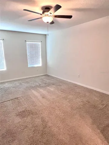 an empty room with windows and fan