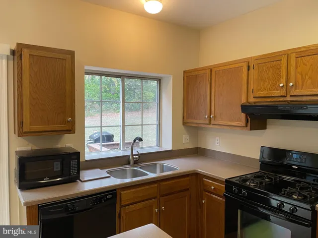 a kitchen with granite countertop a sink a stove and cabinets