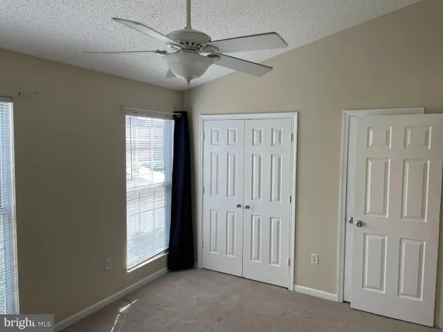 an empty room with windows and fan