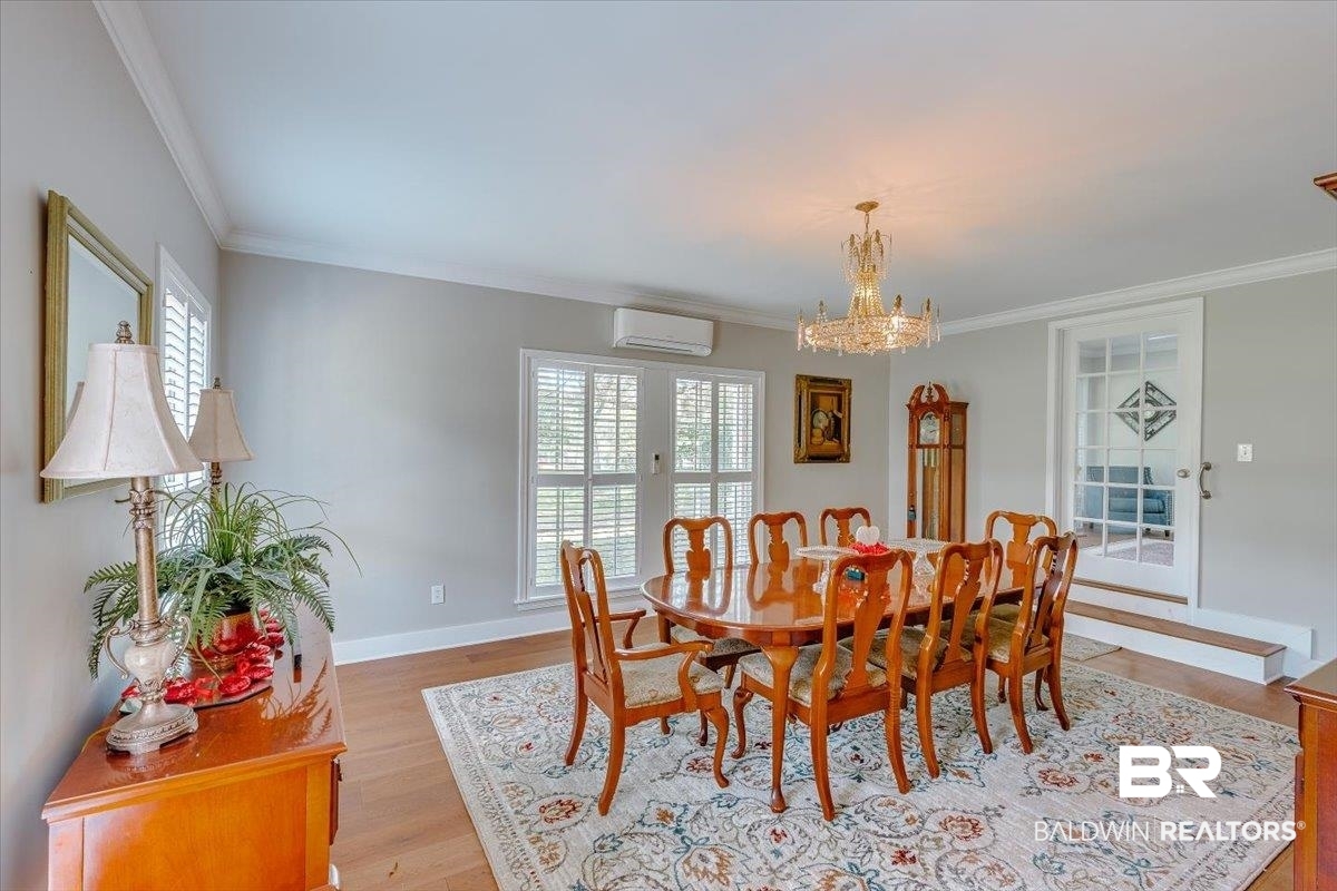 14160 Moffett Road Wilmer, AL 36587 - Photo 18 of 75 Dining space with a notable chandelier, a wall unit AC, light wood-type flooring, baseboards, and ornamental molding