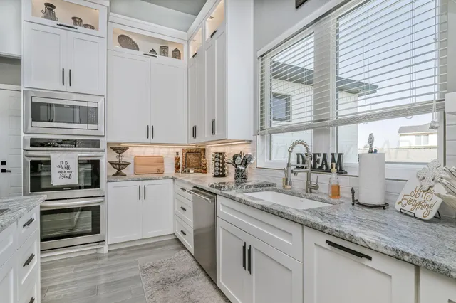 a kitchen with stainless steel appliances granite countertop a sink a stove and cabinets