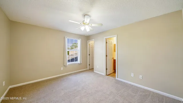 an empty room with chandelier fan and windows