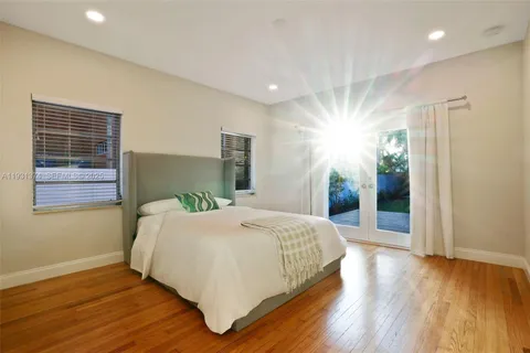 a bedroom with a large bed and wooden floor