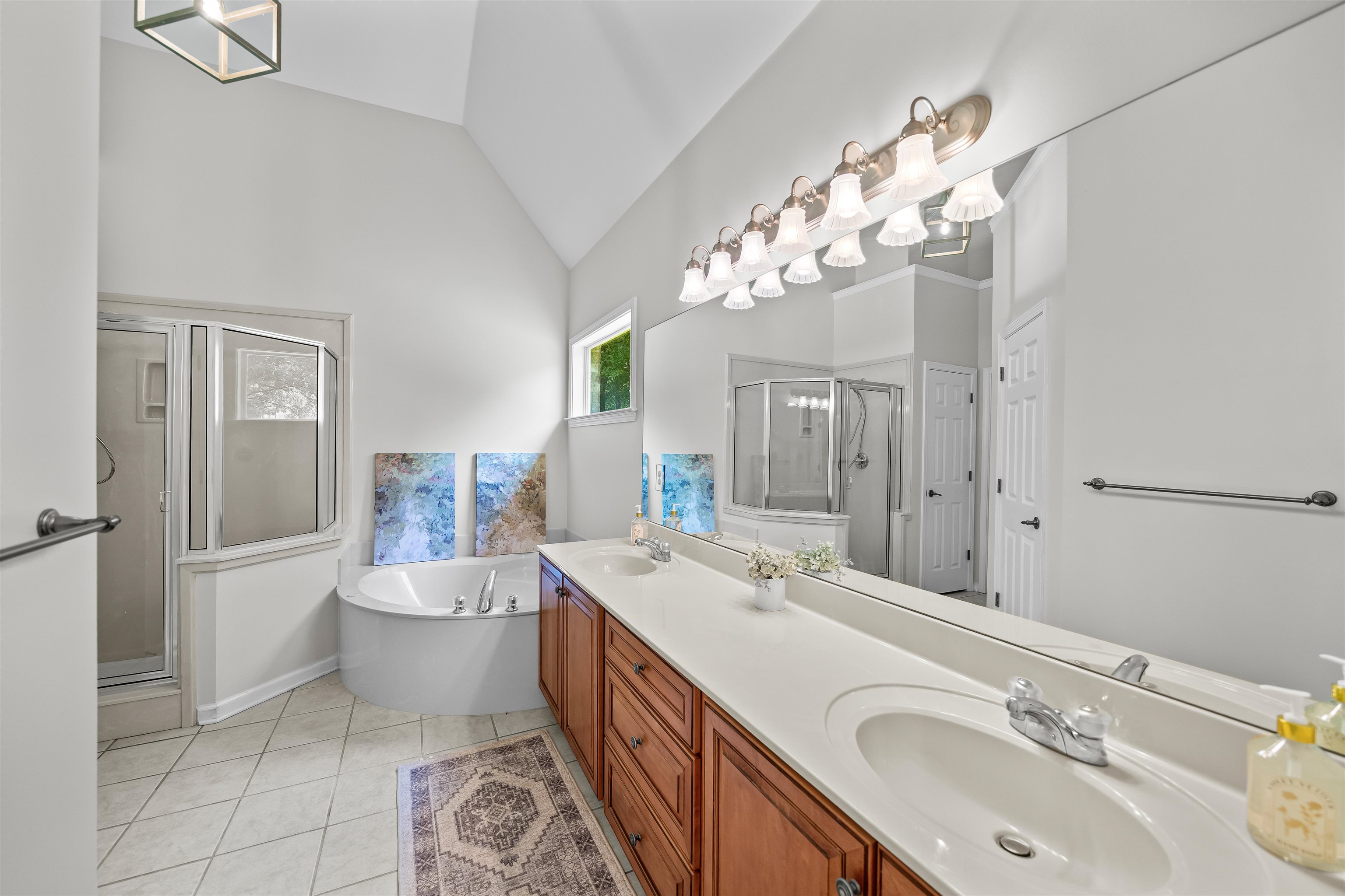 5035 Brian Ridge Road Arlington, TN 38002 - Photo 19 of 40 Vaulted ceiling bathroom featuring a dual vanity with wood cabinetry, a built-in corner bathtub, a glass-enclosed shower, and tiled flooring