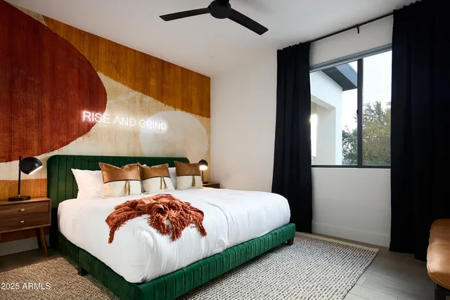 a bedroom with a large bed and a lamp on dresser