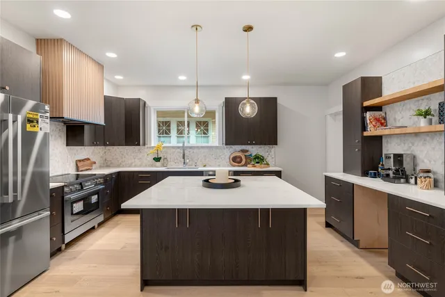 a kitchen with stainless steel appliances kitchen island granite countertop a sink a stove and a refrigerator