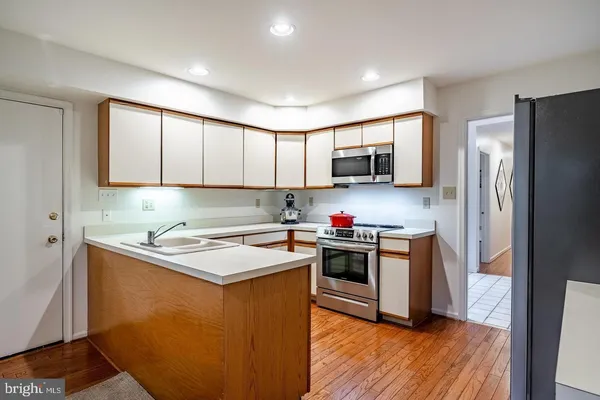 a kitchen with stainless steel appliances granite countertop a stove top oven a refrigerator a sink and dishwasher with wooden floor