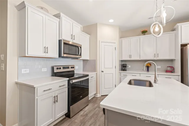 a kitchen with white cabinets and stainless steel appliances