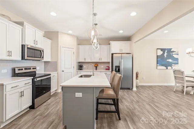 a kitchen with kitchen island a white counter top space stainless steel appliances and cabinets
