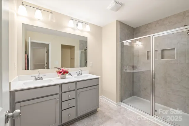 a bathroom with a double vanity sink mirror and shower