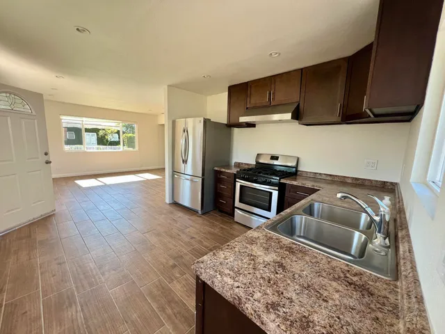 a kitchen with stainless steel appliances granite countertop a sink stove microwave and refrigerator