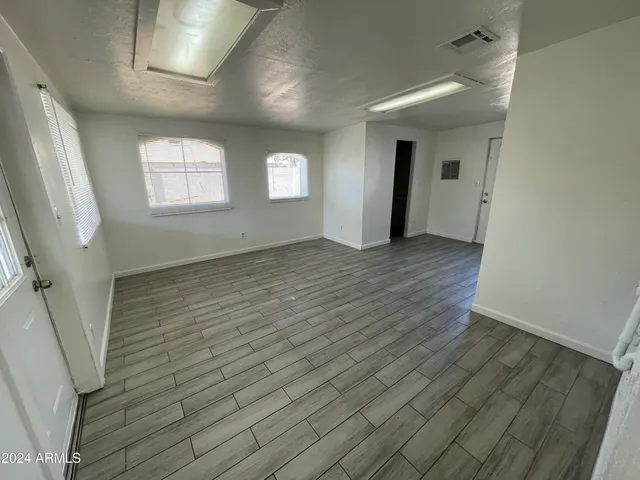 an empty room with wooden floor and windows