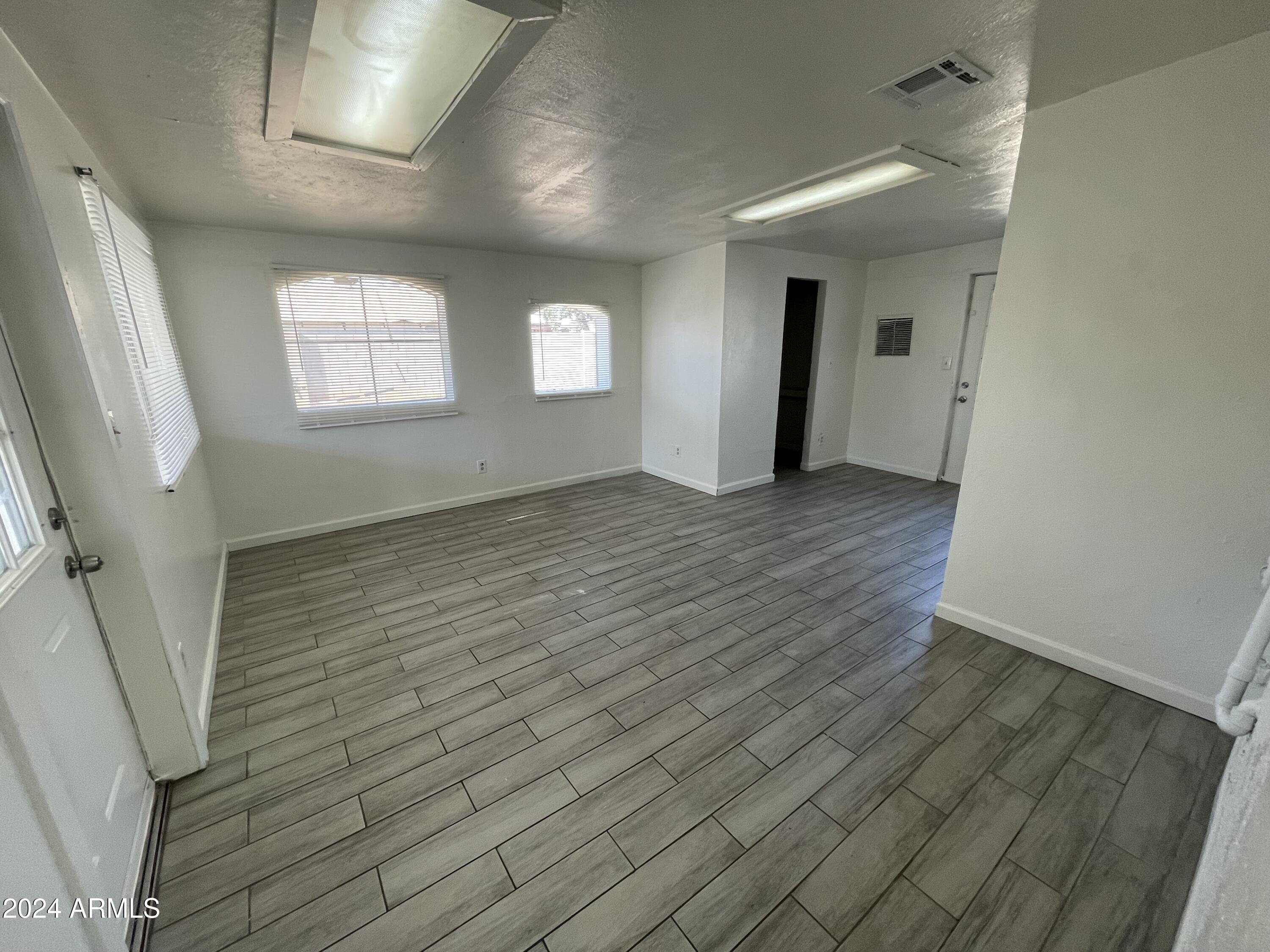 7210 North 55th Drive Glendale, AZ 85301 - Photo 11 of 13 an empty room with wooden floor and windows