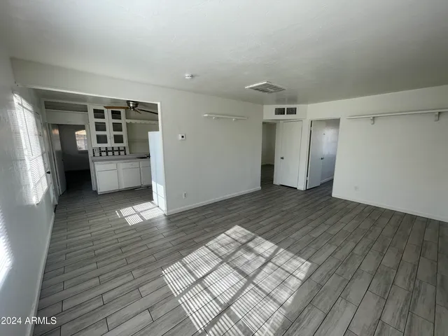 a view of empty room with wooden floor and window