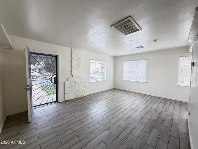 an empty room with wooden floor and windows