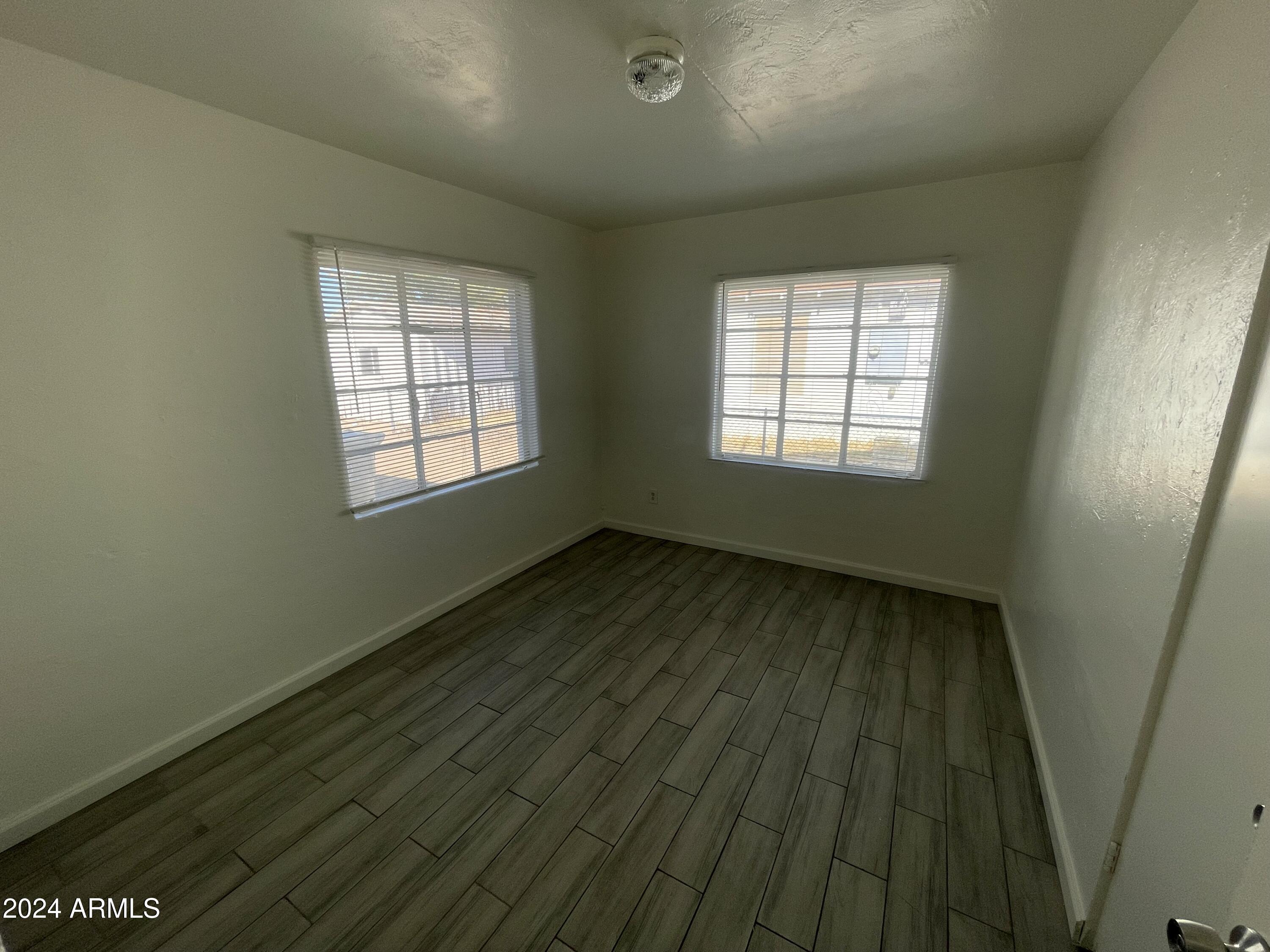7210 North 55th Drive Glendale, AZ 85301 - Photo 7 of 13 an empty room with wooden floor and windows