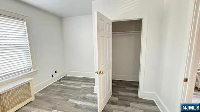 an empty room with a window and hardwood floor