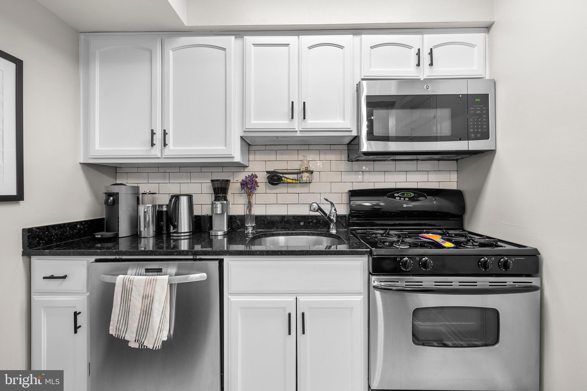 718 Park Road Northwest, Unit 1 Washington, DC 20010 - Photo 18 of 28 a kitchen with granite countertop a stove top oven microwave and cabinets