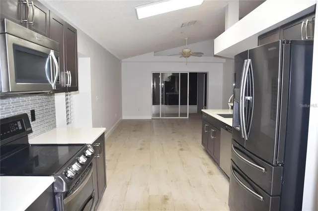 a kitchen with stainless steel appliances granite countertop a refrigerator a stove and a sink with wooden floor