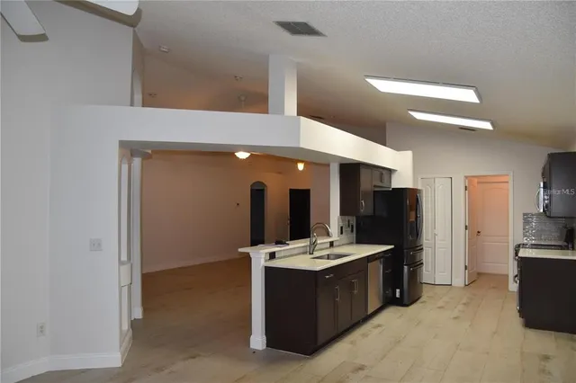 a large room with kitchen island a sink a stove and refrigerator