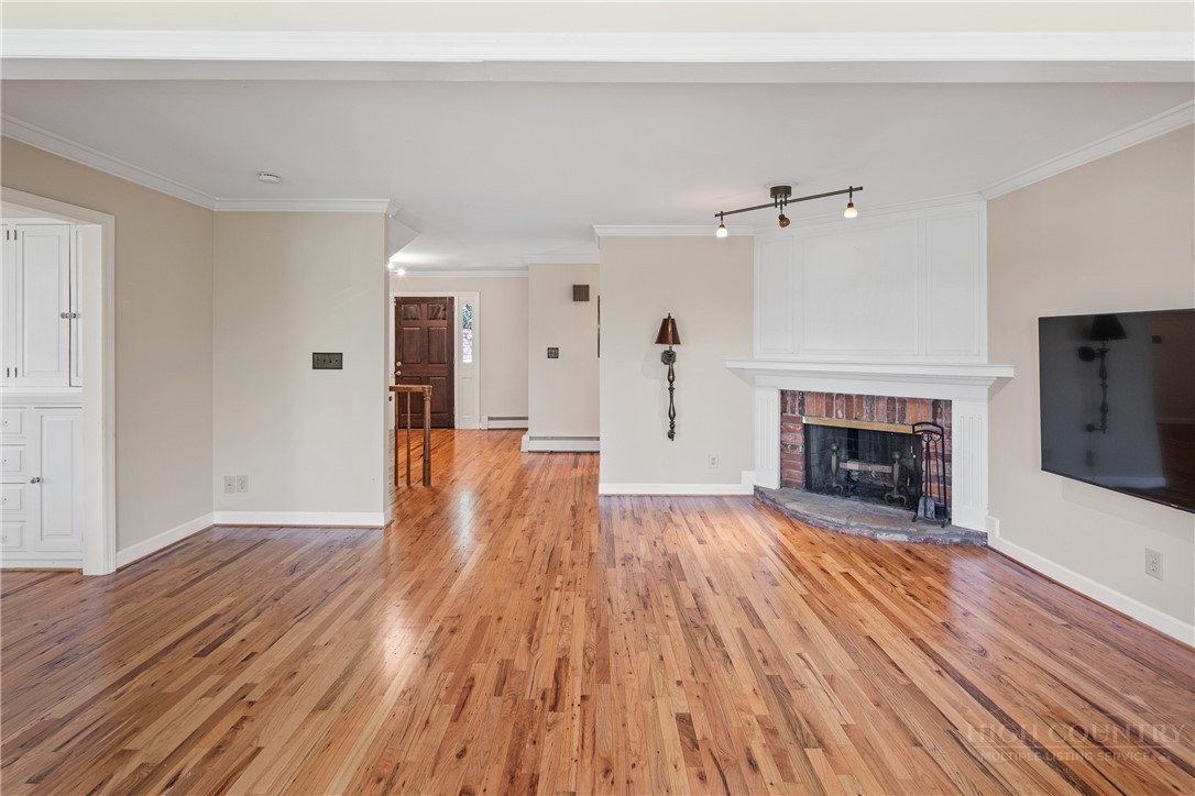 239 Eagle Drive Boone, NC 28607 - Photo 7 of 41 an empty room with wooden floor fireplace and windows