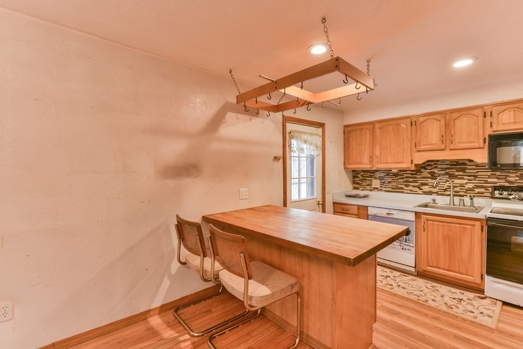 136 Pierpont Road Dudley, MA 01571 - Photo 18 of 28 a kitchen with stainless steel appliances kitchen island a wooden floor and white cabinets
