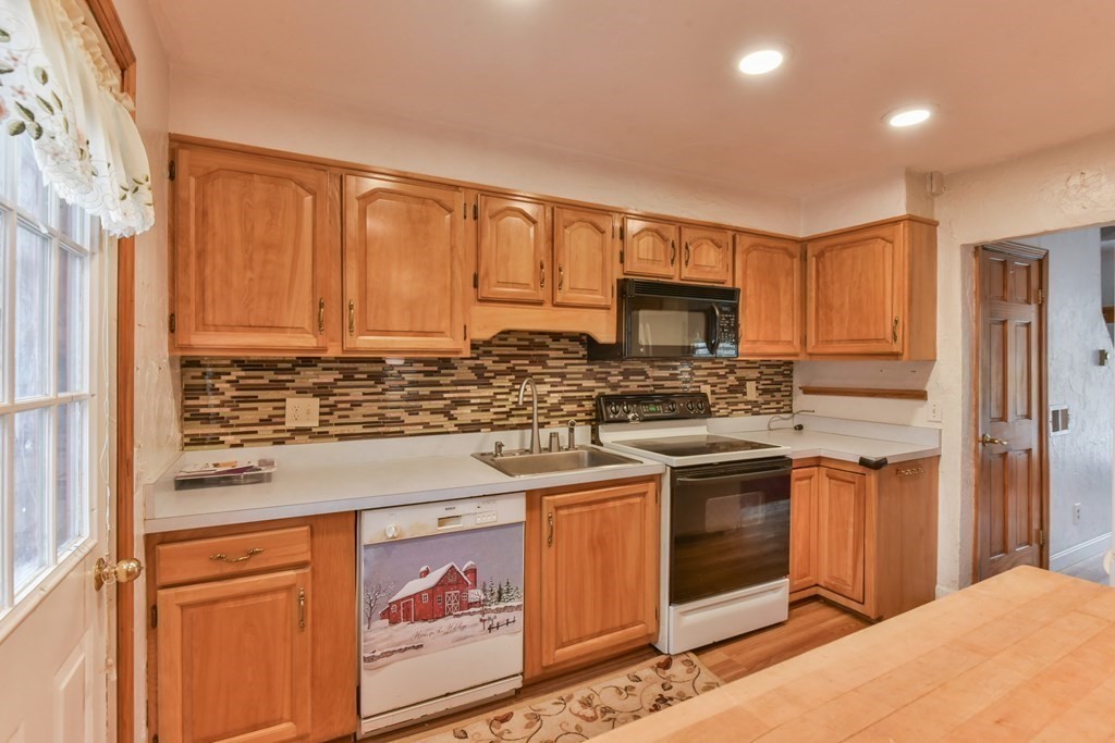 136 Pierpont Road Dudley, MA 01571 - Photo 19 of 28 a kitchen with stainless steel appliances granite countertop a stove a sink and a refrigerator with wooden cabinets