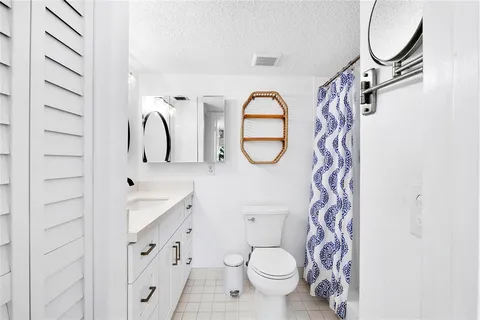 a bathroom with a granite countertop sink a toilet and a mirror