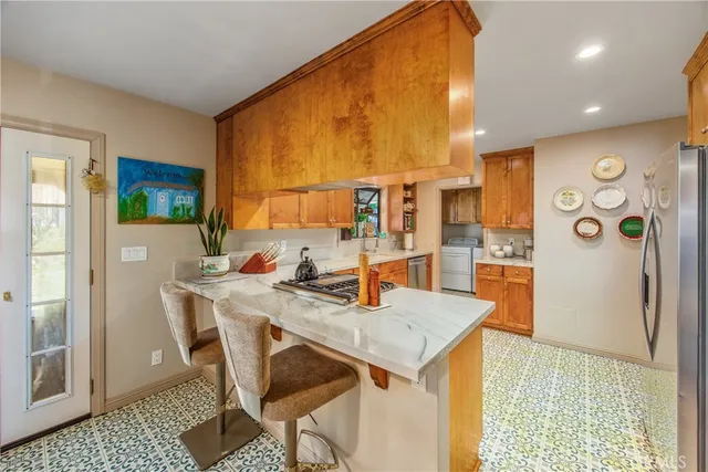 a kitchen with stainless steel appliances kitchen island granite countertop a refrigerator and a stove top oven