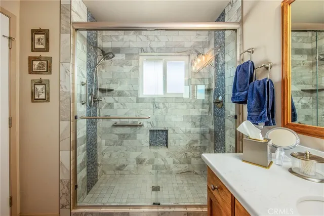 a bathroom with a granite countertop shower a sink and a mirror