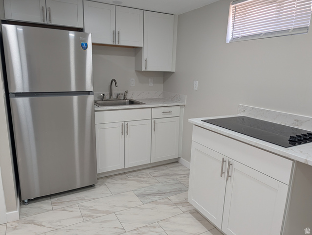 2880 Merton Way Magna, UT 84044 - Photo 15 of 30 Contemporary kitchen featuring white shaker cabinetry, stainless steel refrigerator, stone countertops with integrated backsplash, and a black cooktop