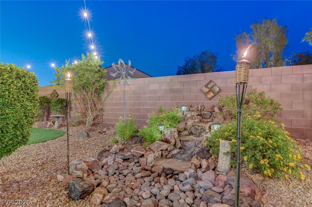 1604 Cattle Ranch Place Henderson, NV 89002 - Photo 95 of 99 A tranquil backyard oasis features a rock waterfall and festive string lights.