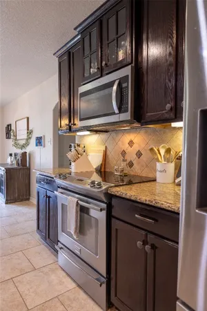 a dining room with kitchen island granite countertop a table chairs and a refrigerator