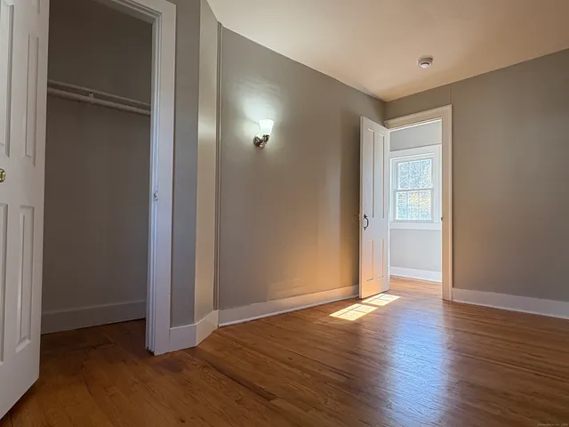 an empty room with wooden floor & closet area